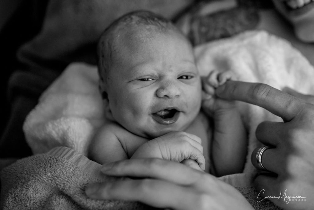 baby smiling holding finger